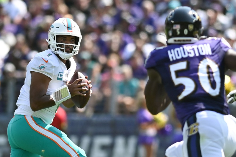 A left-handed quarterback stares down a pass rusher deep in the pocket.