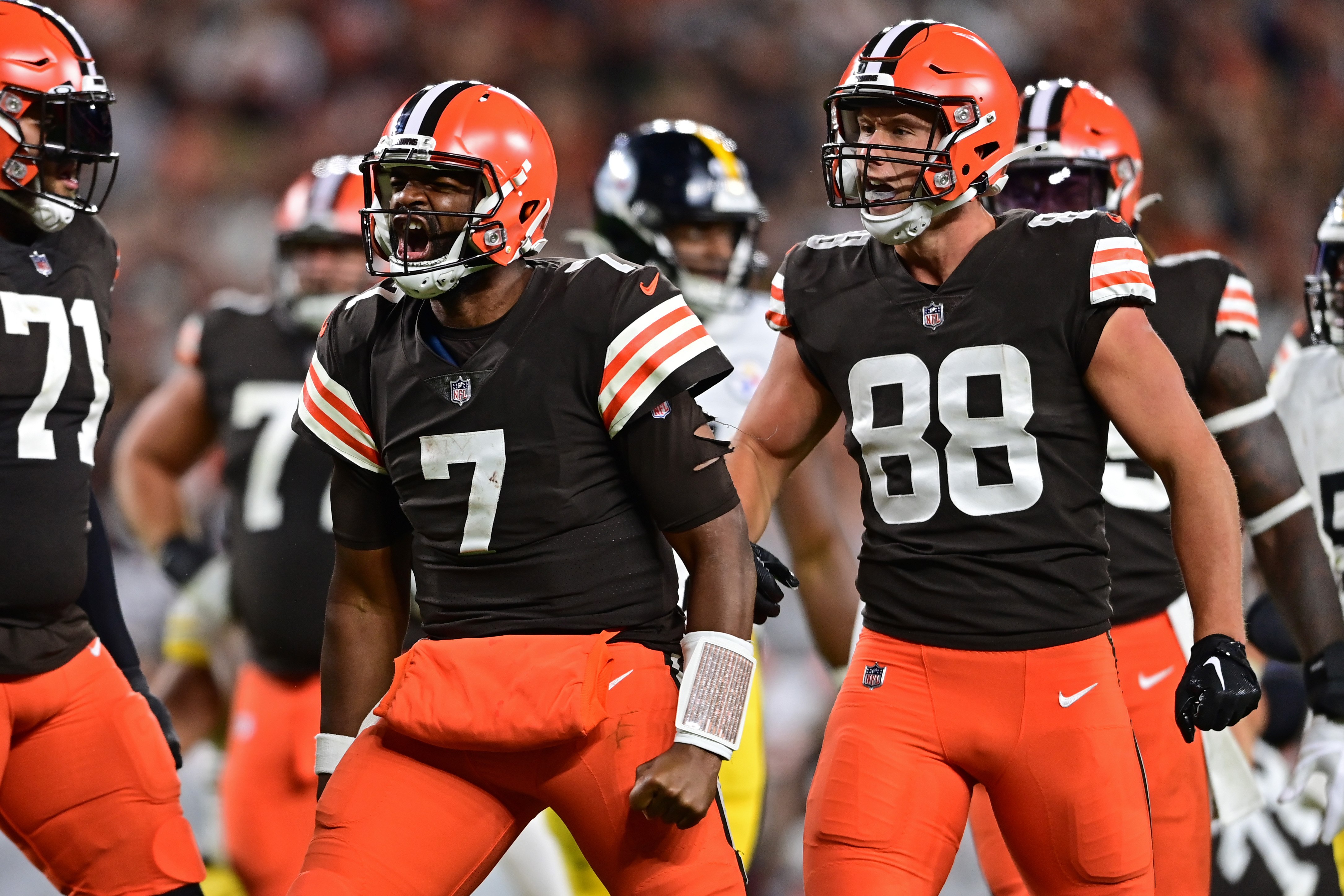 Three Browns players celebrate as Jacoby Brissett, middle flexes in triumph.