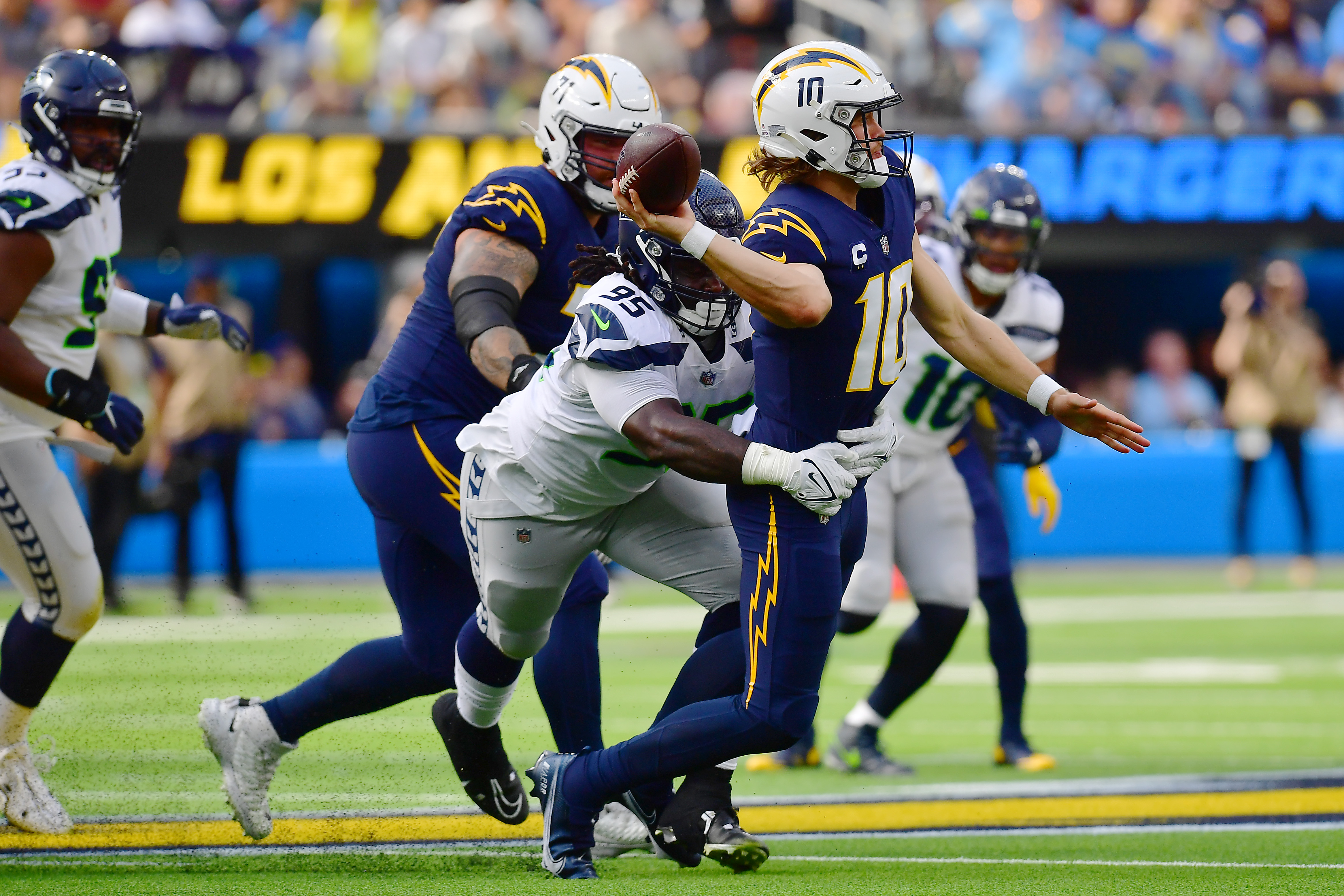 Oct 23, 2022; Inglewood, California, USA; Los Angeles Chargers quarterback Justin Herbert (10) throws under pressure from Seattle Seahawks defensive tackle Myles Adams (95) during the first half at SoFi Stadium. 