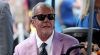 Indianapolis Colts owner Jim Irsay, wearing sunglasses and a pink suit jacket, sits on a golf cart at Dignity Health Sports Park