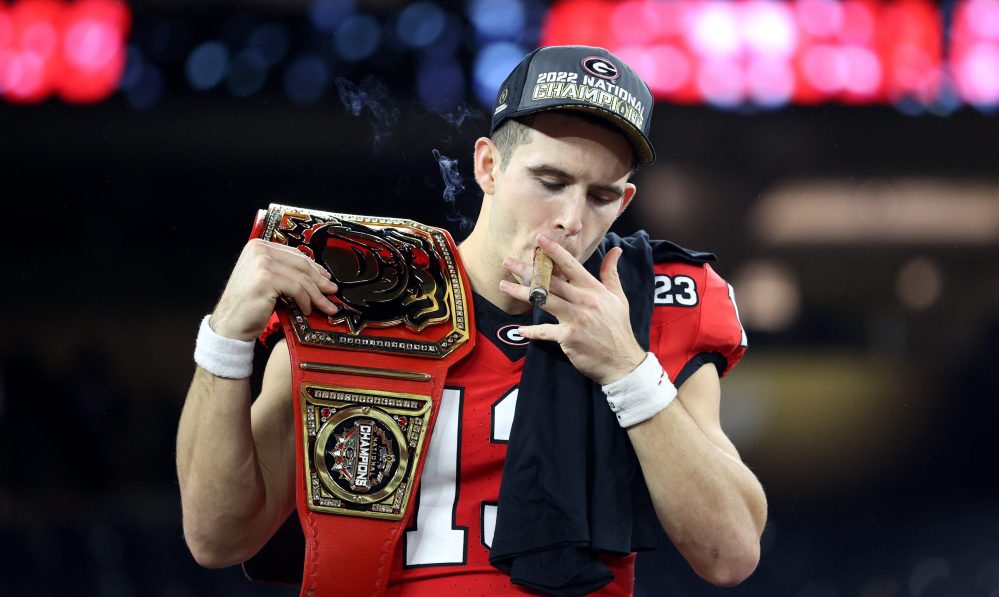 INGLEWOOD, CALIFORNIA - JANUARY 09: Stetson Bennett #13 of the Georgia Bulldogs celebrates with teammates and a cigar after defeating the TCU Horned Frogs in the College Football Playoff National Championship game at SoFi Stadium on January 09, 2023 in Inglewood, California. Georgia defeated TCU 65-7.