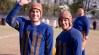 john krasinki and george clooney stand outside in blue football jerseys and brown leather helmets in a scene from leatherheads