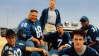 group of men in blue football jerseys in a promotional photo from varsity blues
