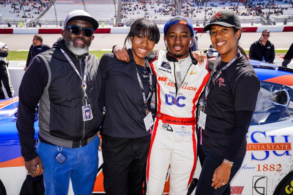Rajah Caruth stands near his race car at a track with his father, sister and mother