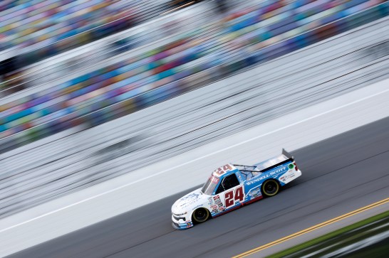 A truck speeds down a race track with the crowd blurred behind it