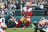 Wearing a white jersey and gold pants, 49ers wideout Deebo Samuel carries the ball in the 2023 NFC Championship game against the Eagles.