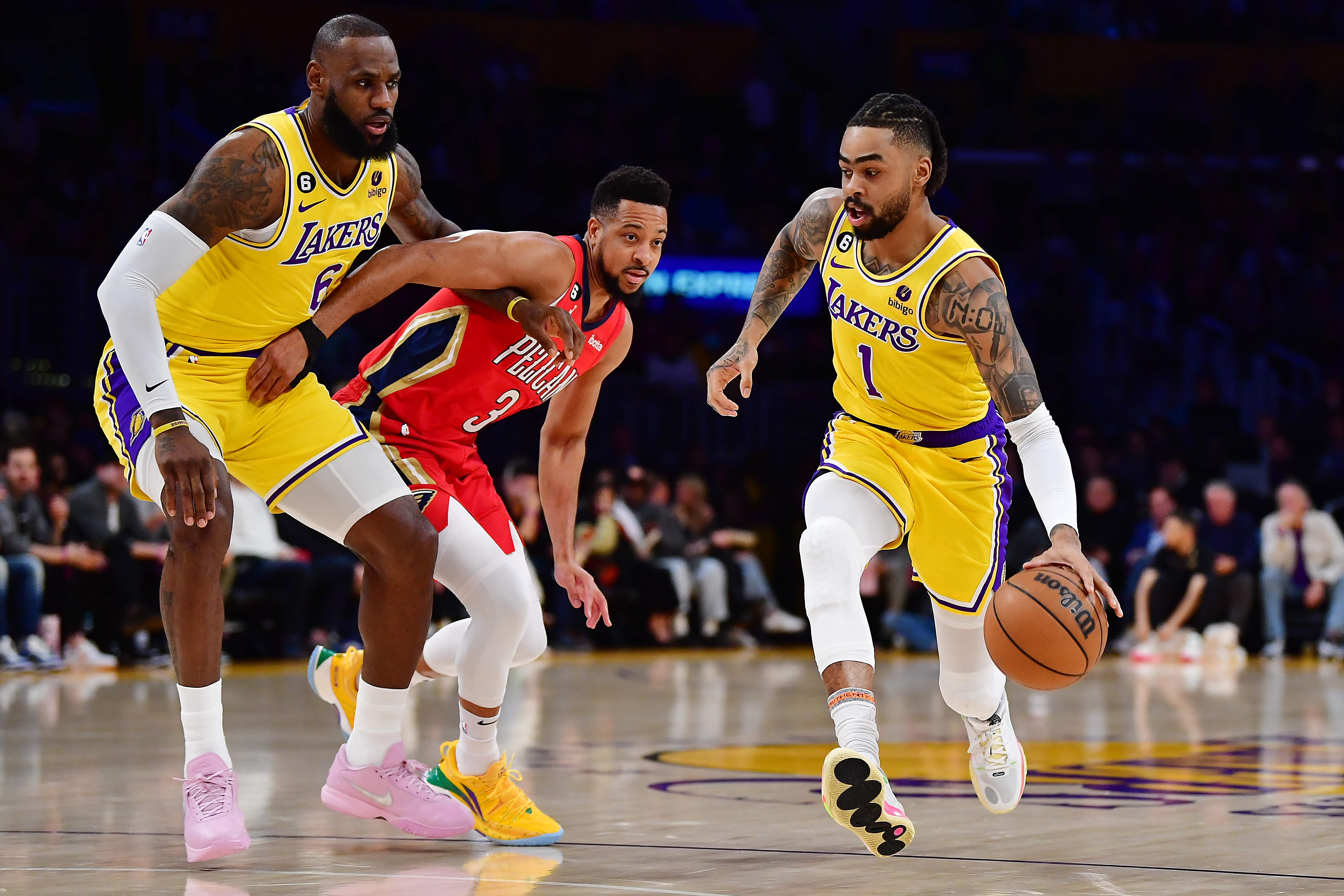 D'Angelo Russell dribbles the ball past C.J. McCollum as LeBron James looks on.