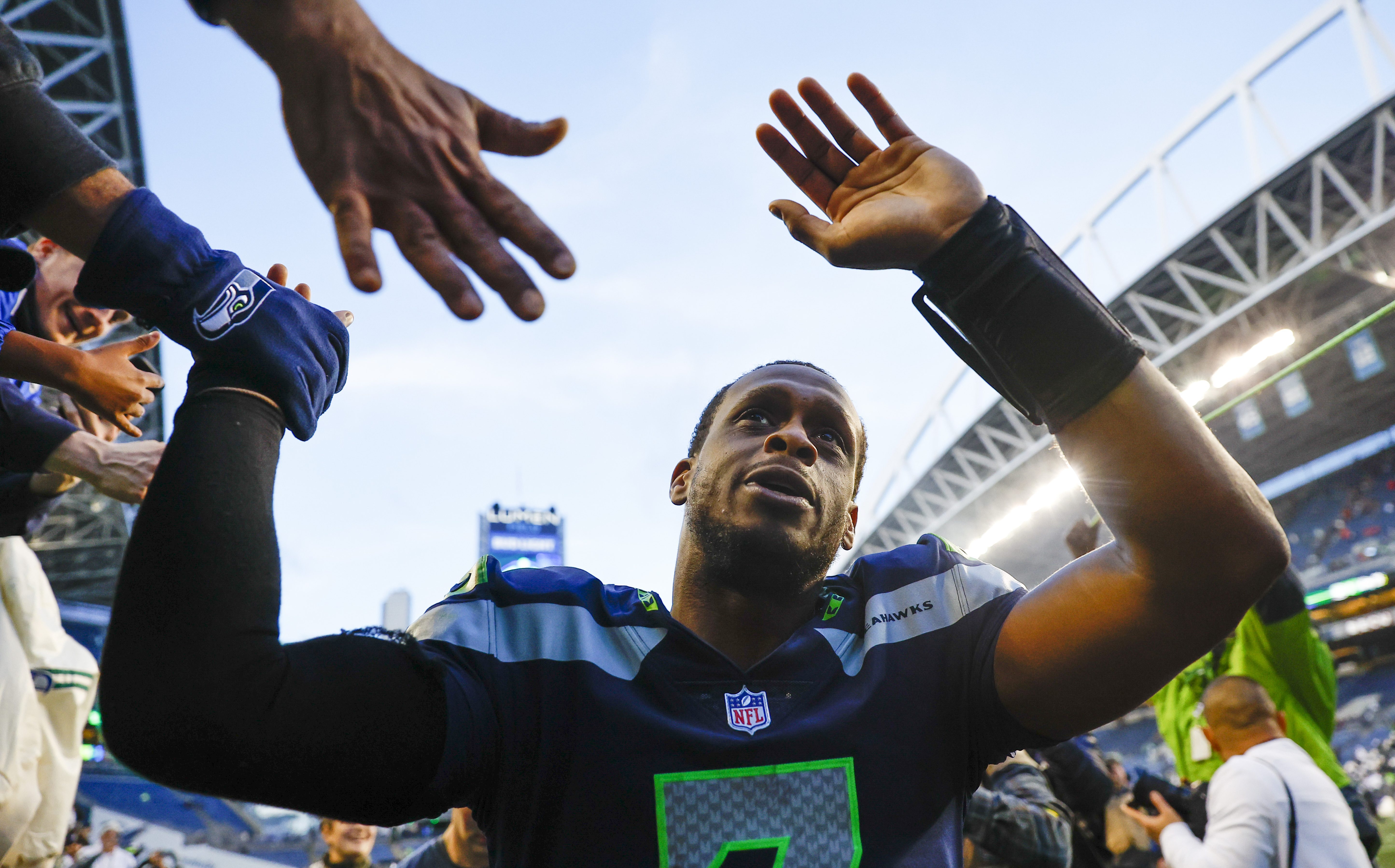 Geno Smith high-fiving fans after a 2022 season game with the Seahawks
