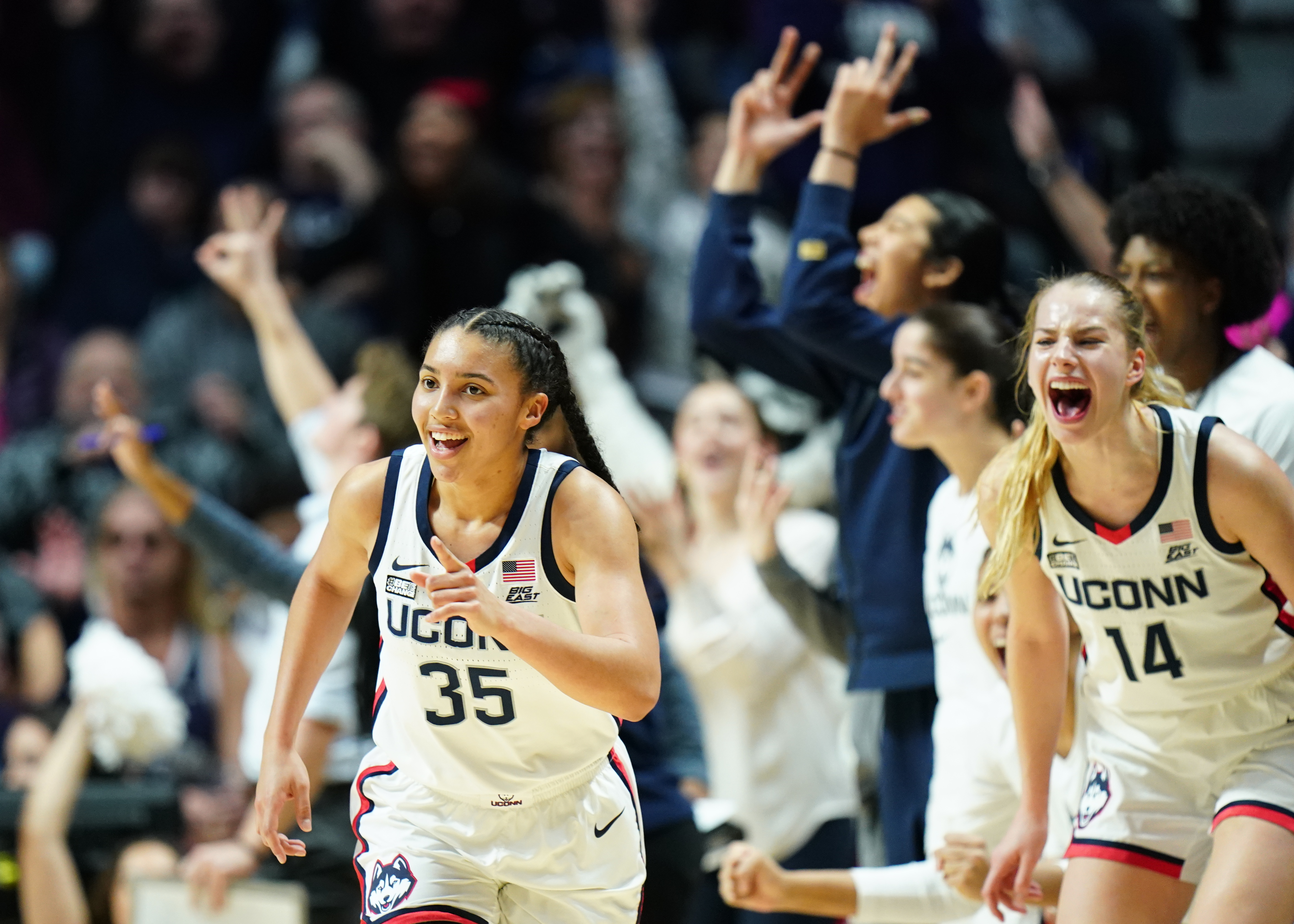 UConn Huskies guard Azzi Fudd, wearing a white jersey, reacts after a 3-pointer.