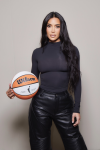 Kim Kardashian dressed in a black top and black leather pants, holding a Wilson WNBA basketball