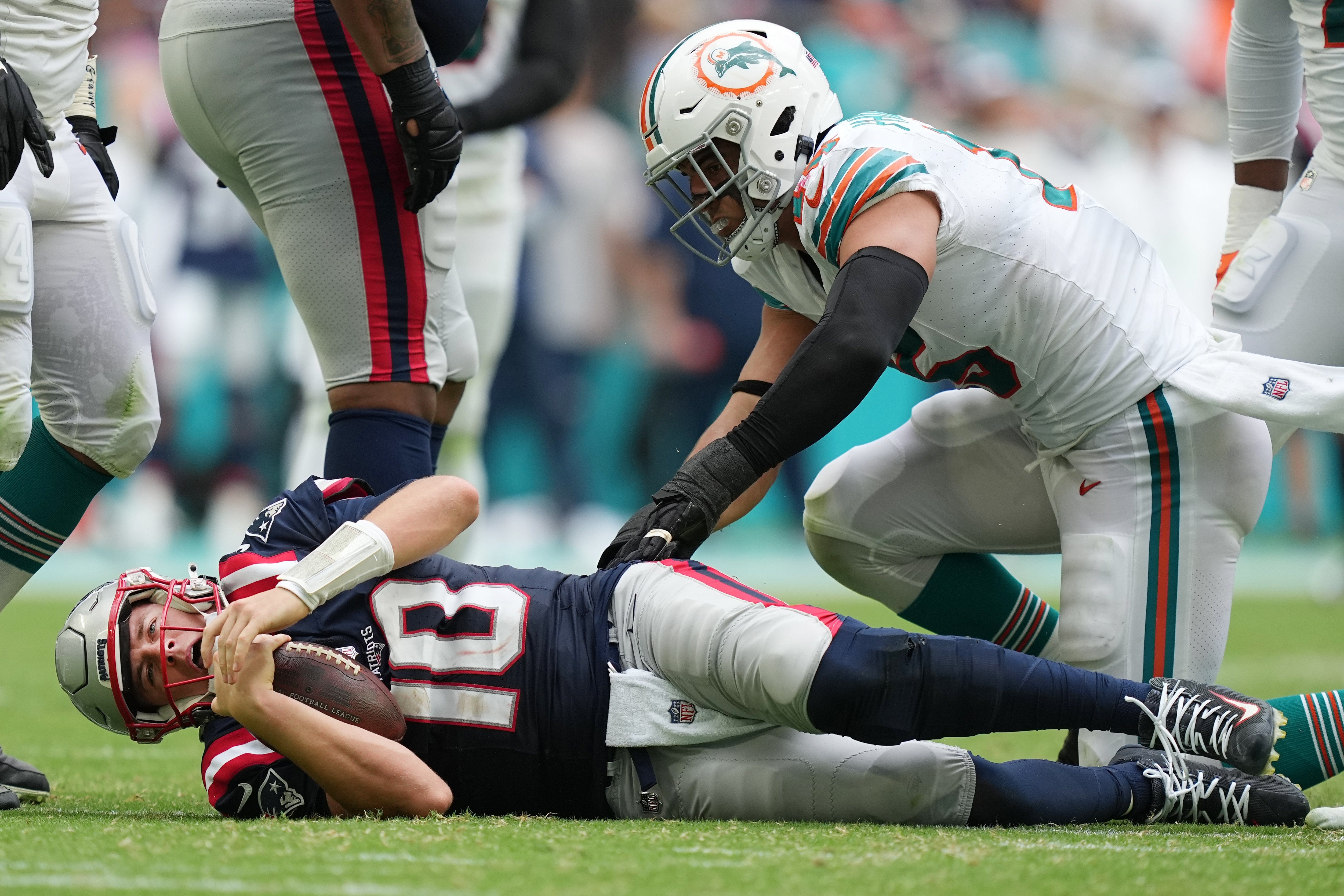 New England Patriots quarterback Mac Jones (10) gets up slow after being sacked by Miami Dolphins linebacker Jaelan Phillips (15) during the second half of an NFL game at Hard Rock Stadium in Miami Gardens, Oct. 29, 2023.
