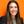 WNBA Chief Growth Officer Colie Edison, smiling and wearing a black jacket with a gray shirt, against an orange background