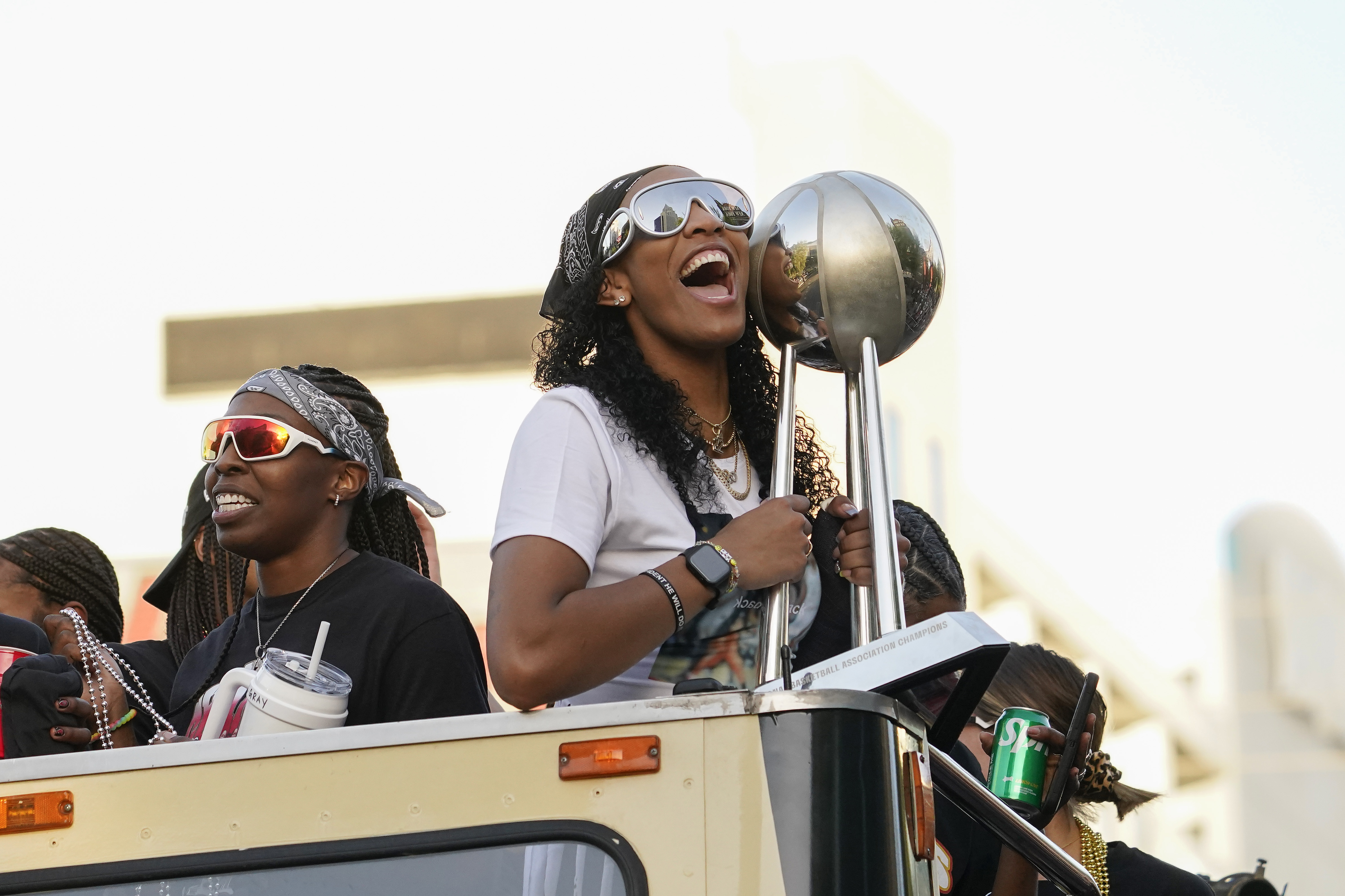 Las Vegas forward Aj'a Wilson holding the WNBA Championship trophy while riding in a double-decker bus on the Las Vegas Strip