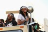 Las Vegas forward Aj'a Wilson holding the WNBA Championship trophy while riding in a double-decker bus on the Las Vegas Strip